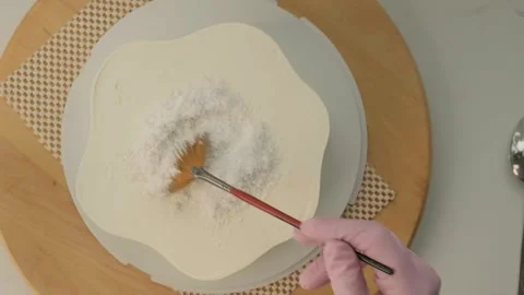 Pastry chef decorating a cake with coconut flakes on the rotating cake stand Stock Footage 303970837
