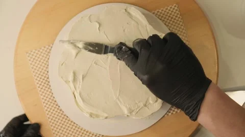 Pastry chef decorating a cake with cream cheese on the rotating cake stand Video stock 306918955