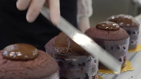 Pastry chef is decorating chocolate cake with liquid chocolate pouring it on the 스톡 동영상 160496845