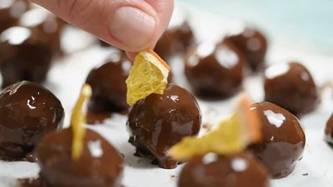 The pastry chef decorating chocolate truffles with orange chips. Video stock 244387178