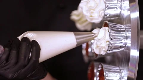 Pastry chef decorating cupcake with whipped cream vertical video Stock Footage 297624086