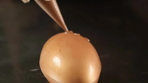 Pastry chef decorating golden egg shaped dessert with chocolate Stock Footage 306587463