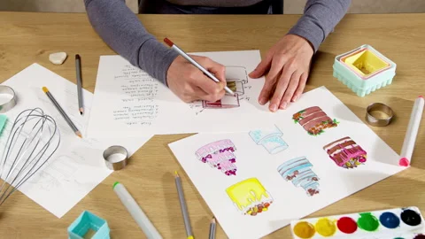 The pastry chef develops a cake design by drawing on paper.  Stock Footage 253318724