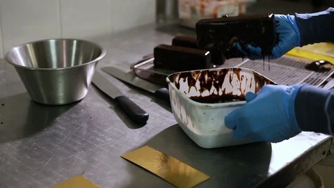The pastry chef dips the cake into liquid chocolate  and outs it on a tray Stock Footage 106482143