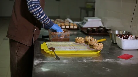 The pastry chef dips the cake in liquid chocolate and puts it on a tray Stock Footage 106482300