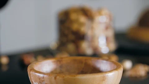 Pastry chef is dips a hazelnut in caramel for making topping for a cake Stock Footage 124901314