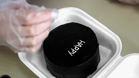 The pastry chef draws on a black cake Stock Footage 255421038