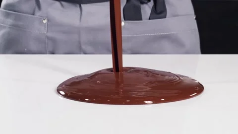 Pastry chef in grey uniform tempering melted chocolate on a white stone table Video stock 151361322
