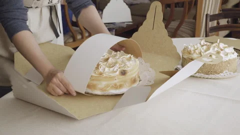 Pastry chef hands arranges cake with roasted meringue topping in box Stock Footage 240119950