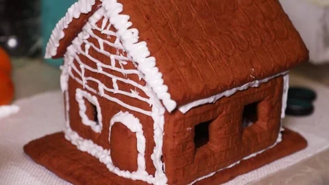 Pastry Chef Hands Decorating Gingerbread House Roof Edges with Frosting Stock Footage 345634279