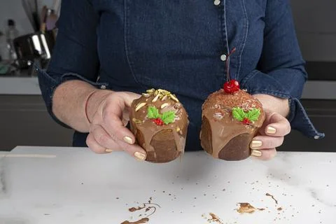 A pastry chef holding two small panettone cakes covered in melted chocolate. Stock Photos
