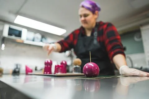 Pastry chef kitchen interior. Decorating process. Caucasian woman covering Stock Photos