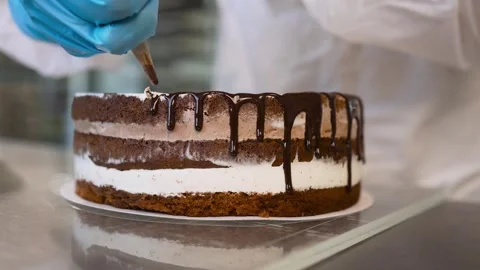 The pastry chef makes smudges of liquid chocolate icing on the cake to decorate Video stock 274089870