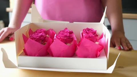 Pastry chef opens delivery box with pink cupcakes with rose buds on the top Stock Footage 152854002