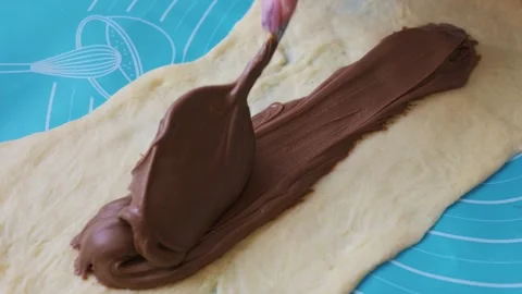 Pastry Chef Piping Chocolate Hazelnut Spread Onto Dough Layer on Blue Baking Mat Stock Footage 334119494