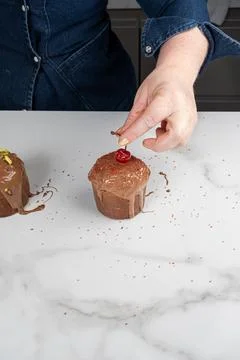 A pastry chef placing a fresh cherry on top of the small panettone vertical. Stock Photos