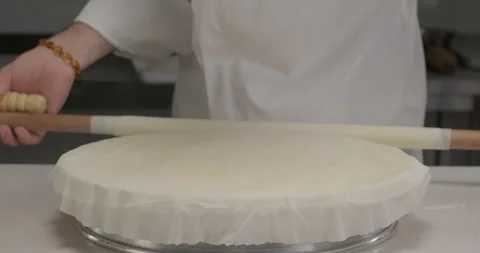 Pastry chef prepares Turkish dessert baklava, arrange phyllo dough sheets on a Stock Footage 294246445