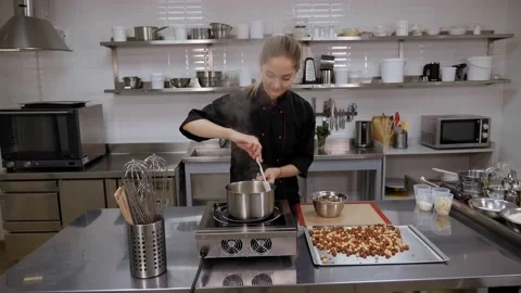 Pastry chef preparing caramel in a pastry kitchen, she mixes sugar in a pan. Stock Footage 136845652
