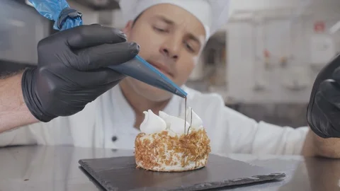 Pastry chef preparing dessert at table in kitchen enjoying process Stock Footage 125051623
