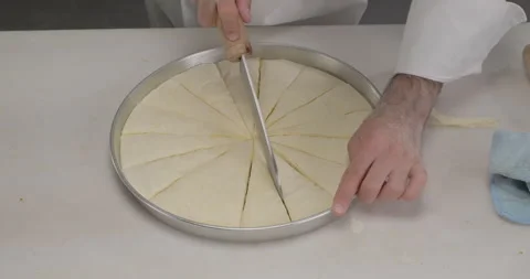 Pastry chef preparing Turkish dessert baklava, cut raw baklava in a tray Stock Footage 298270965
