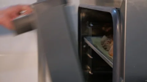 Pastry chef pulls out of the oven baking sheet with cinnamon rolls. Stock Footage 106004061