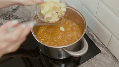 The pastry chef puts butter into a boiling sugar to make homemade caramel sauce Stockbeeldmateriaal 197371379