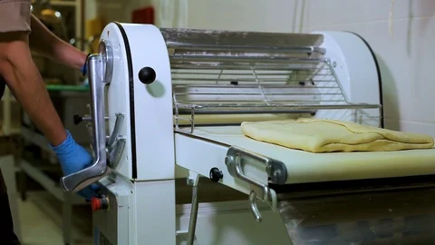 The pastry chef roll out the dough with a big Dough sheeter Stock Footage 106463547