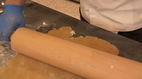 Pastry chef is rolling the dough with the rolling pin on the table. 库存影片 125068999