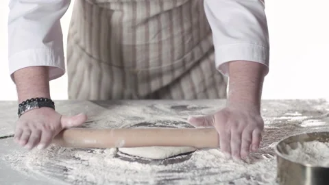 Pastry chef is rolling the dough with the rolling pin on the on the table. Hands Stock Footage 169294319