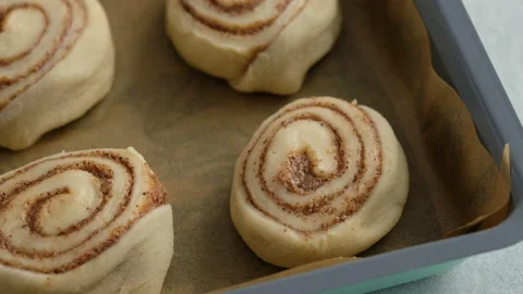 Pastry chef rolls cinnamon dough roll for buns. Female hands preparing cinnabon Stock Footage 141370031