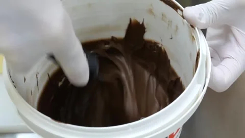 Pastry Chef Scooping Smooth Melted Chocolate from Bucket, Close-up Stock-Footage 345651501