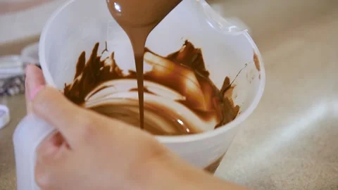 A pastry chef in slow motion applies chocolate to a confection. Close-up Video stock 146802940