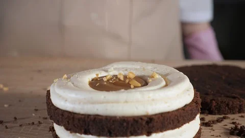 Pastry chef is sprinkle with peanuts on chocolate sponge cake. Making cake Vídeo Stock 106003905