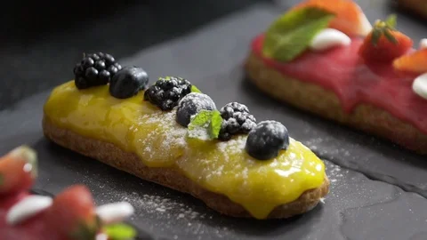 Pastry chef sprinkle with powdered sugar to cooked eclair Stock Footage 95931206