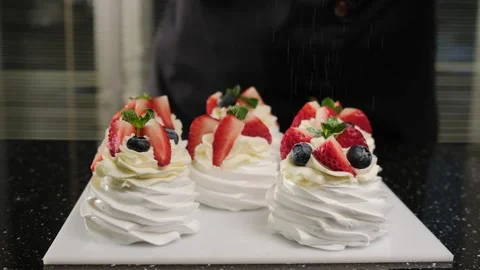 The pastry chef sprinkle powdered sugar on Anna Pavlova's mini cakes. Stock Footage 149185298