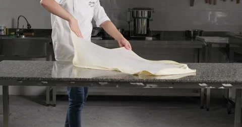 Pastry chef stretches phyllo dough to prepare traditional Turkish dessert Stock Footage 288031316