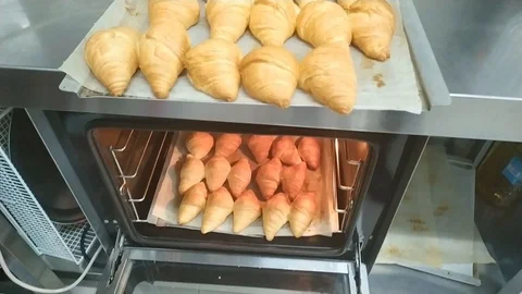 Pastry chef taking freshly made croissants from the oven. Stock Footage 125612556