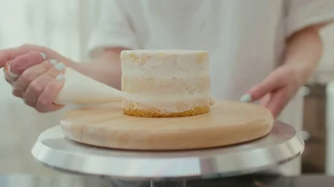 The pastry chef turns the table and smears the cake with delicious whipped cream 库存影片 194393847