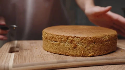 The pastry chef is using a knife to score the cake layer, in order to divide it Stockbeeldmateriaal 240299582