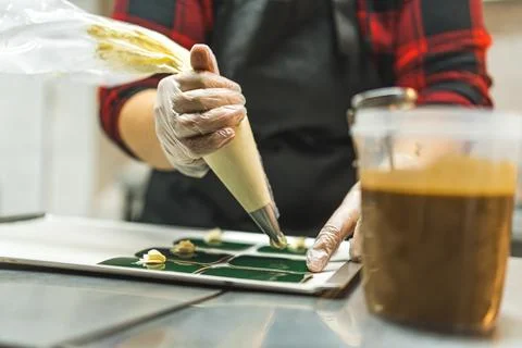 Pastry chef using pastry bag filled with white buttercream frosting. Bakery Stock Photos