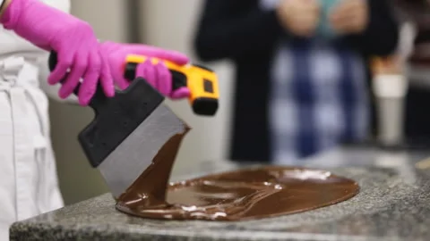 Pastry chef in white uniform tempering chocolate on a marble plate Stock Footage 121034646