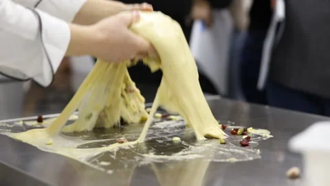 The pastry chef works with a batch of dough on the working surface. Stock Footage 121035634
