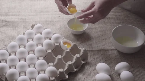 Pastry chef's hand breaks egg in the corner of a small container Stock Footage 240660962