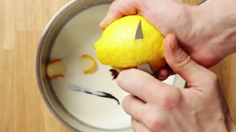 Pastry chef's hands cut and add lemon peel to milk mixture. Stock Footage 345273895