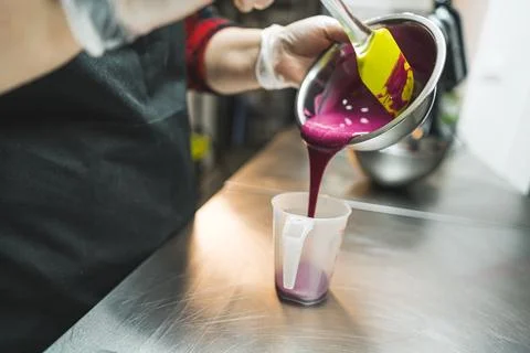 Pastry decorating. Pastry chef posing prepared melted pink icing from a bowl to Stock Photos