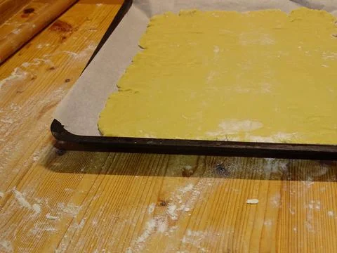 Pastry dough placed into a baking tray on a floured rustic wooden surface Stock Photos
