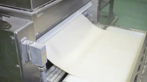 Pastry running through a machine at a commercial bakery Stock Footage 1097395
