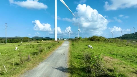 A pasture road, with a windmill rotating in the background. Video stock 283850172