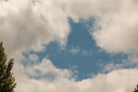 A patch of blue sky surrounded by clouds Stock Photos