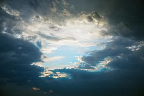 Patch of clear blue sky after a storm on a dark cloudy sky Stock Photos